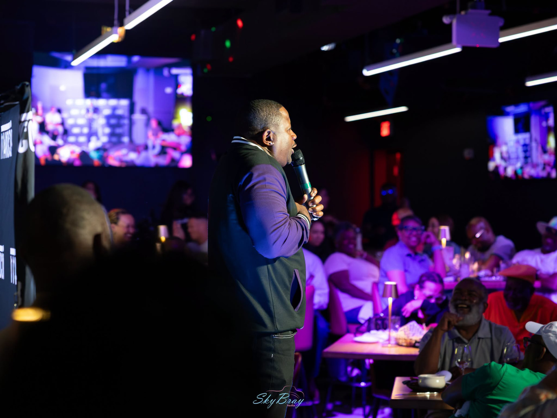 A comedian performing for a seated audience at an intimate venue